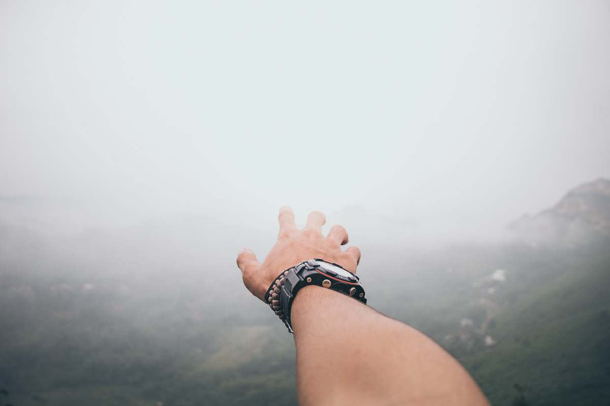 reaching out person wearing black watch fog